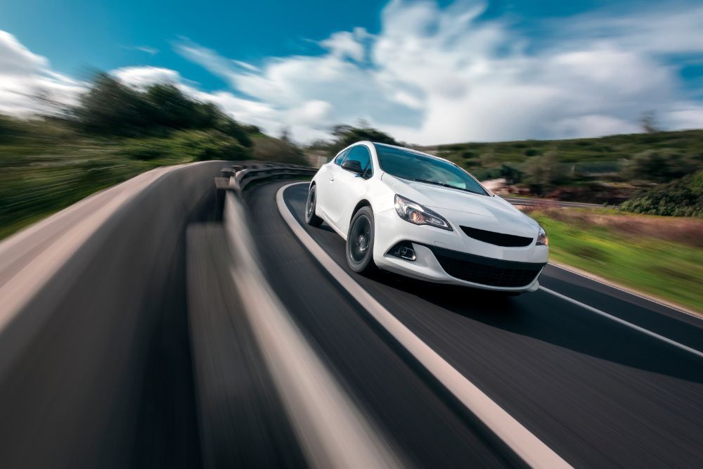 White car cornering in mountain road with speed blur