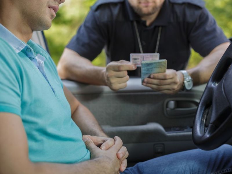 Stopped young driver with a police officer looking at his drivers license
