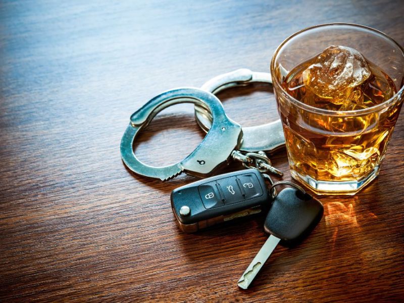 a pair of car keys next to an alcoholic drink and hand cuffs