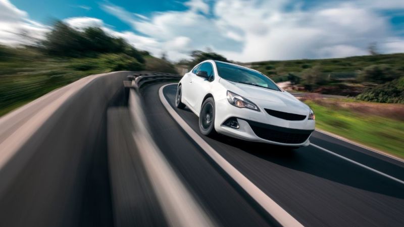 White car cornering in mountain road with speed blur
