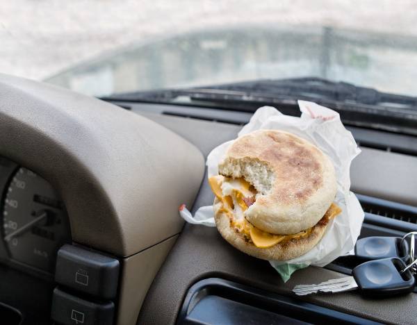 Breakfast sandwich sits on a car dashboard with keys